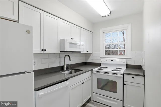 a kitchen with granite countertop white cabinets and white appliances