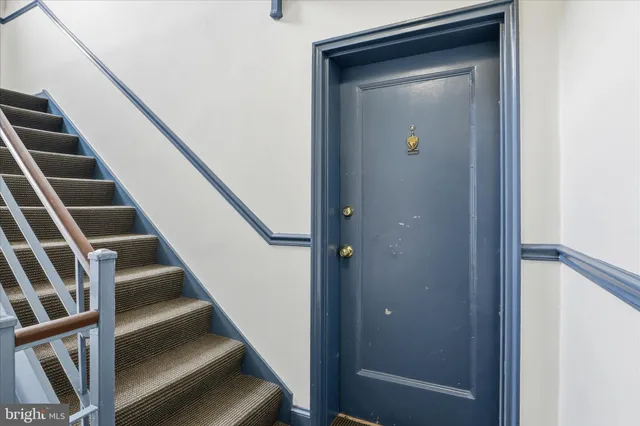 a view of staircase with wooden floor and lots of frames on wall