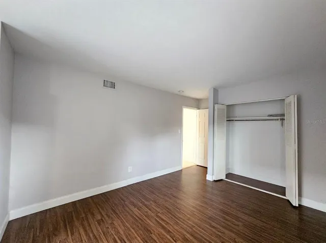 a view of an empty room with wooden floor and closet
