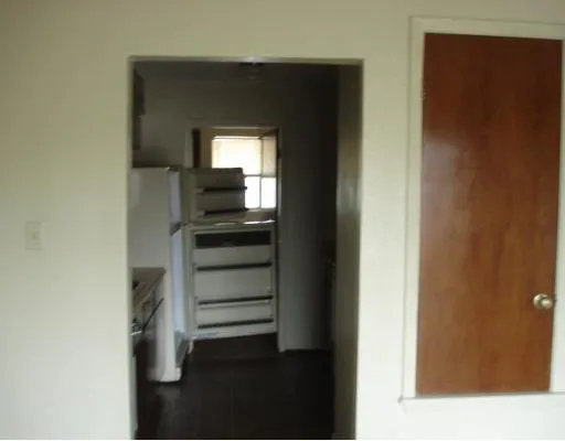 a view of a hallway with wooden floor and a bathroom