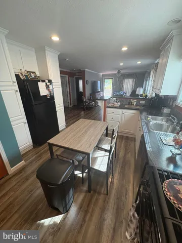 a kitchen with stainless steel appliances granite countertop a stove a refrigerator a sink a dining table and chairs with wooden floor