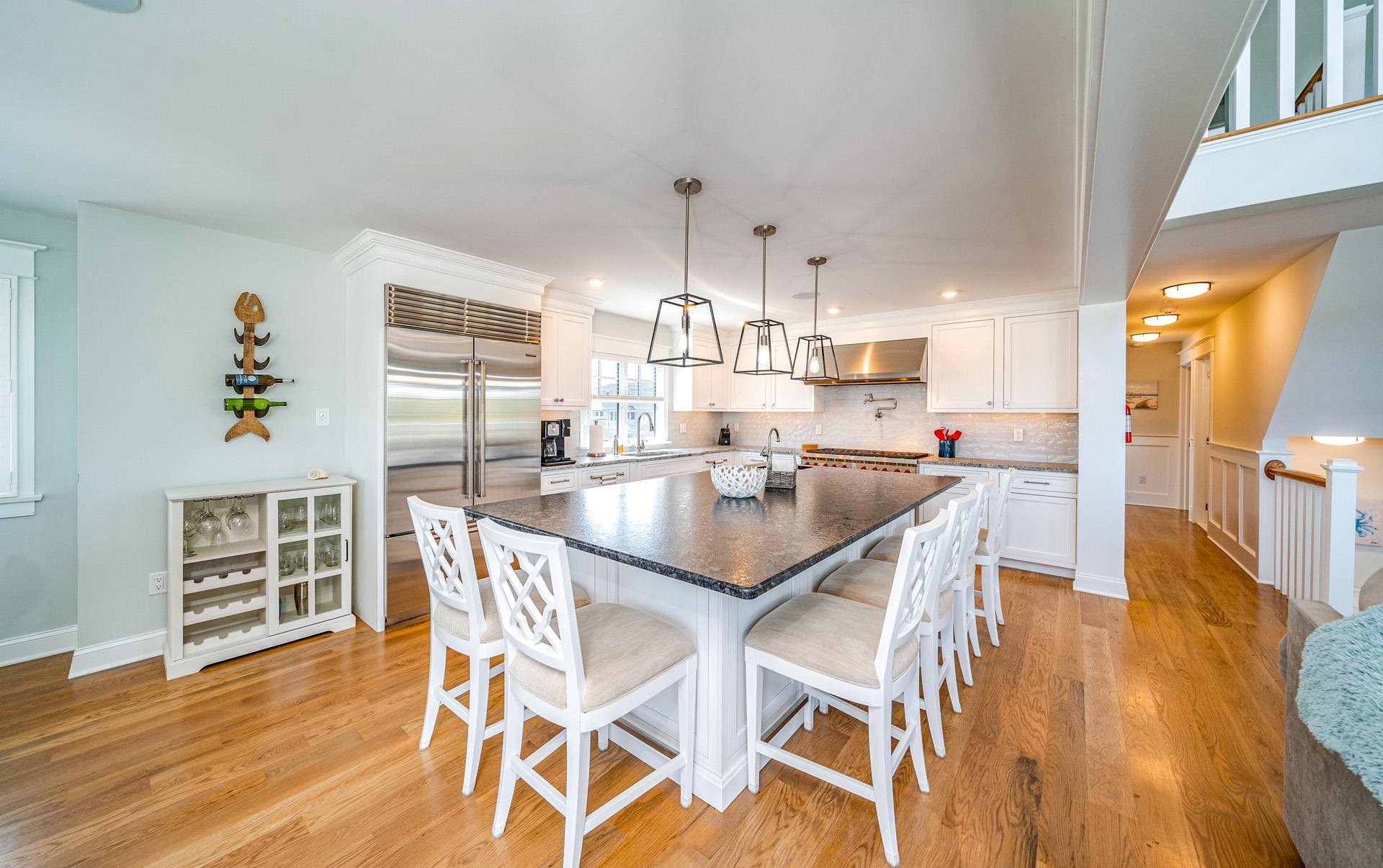 7418 Dune Drive Avalon, NJ 08202 - Photo 32 of 50 a kitchen with stainless steel appliances kitchen island granite countertop a table chairs in it and wooden floors
