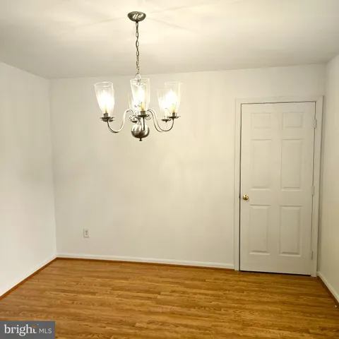 a view of empty room with wooden floor and kitchen view