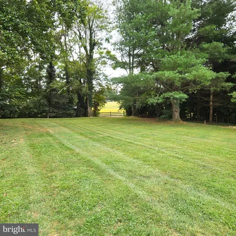 a view of a field with trees in front of the house