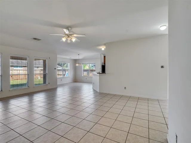 a view of an empty room with a window and a kitchen