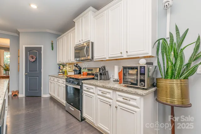 a kitchen with stainless steel appliances granite countertop a stove a sink and a white cabinets