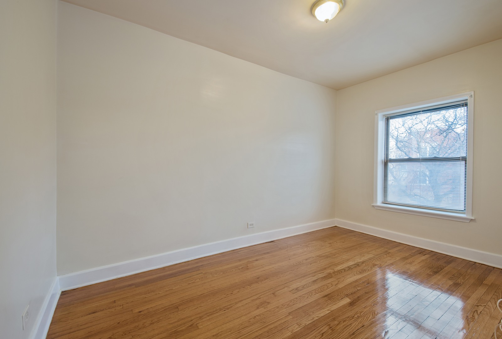 115 East 60th Street, Unit 2 Chicago, IL 60637 - Photo 6 of 8 an empty room with wooden floor and windows