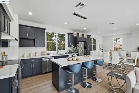 a open dining room with stainless steel appliances kitchen island granite countertop a table chairs and a microwave