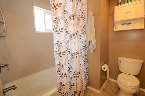 a white toilet sitting next to a bath tub and a shower curtain