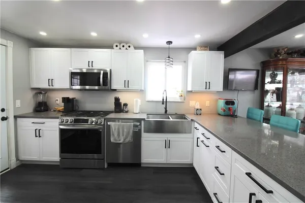 a large kitchen with stainless steel appliances granite countertop a stove a sink and a white refrigerator