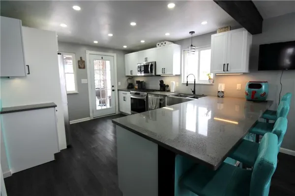 a kitchen with stainless steel appliances granite countertop a refrigerator a stove top oven a sink a stove and island with wooden floor