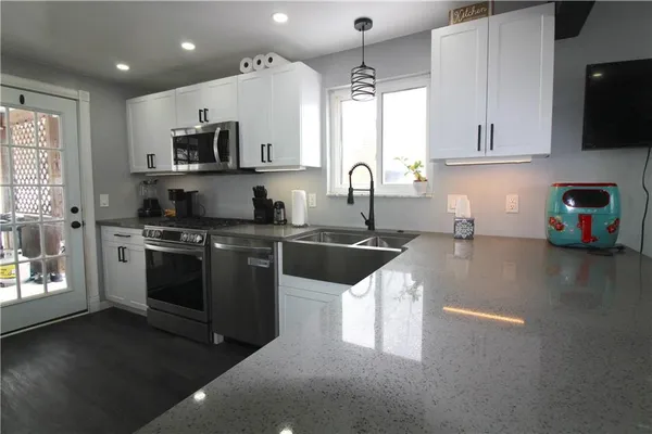 a kitchen with stainless steel appliances granite countertop a sink a stove top oven a counter space and cabinets
