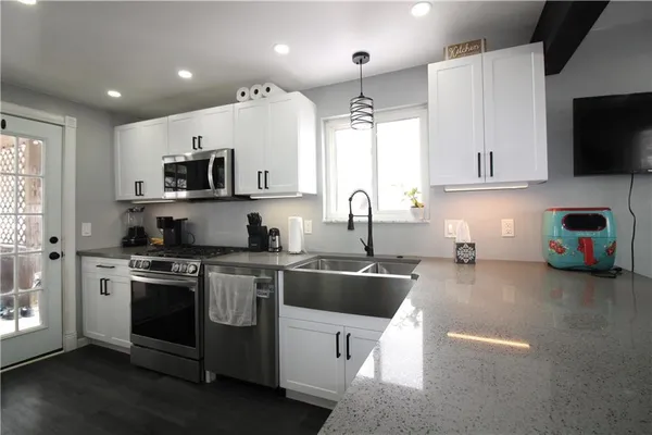 a kitchen with stainless steel appliances a stove a sink a microwave a refrigerator and cabinets