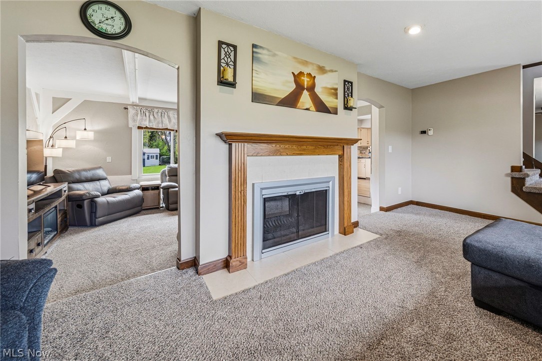 10610 Ridgewater Drive Painesville, OH 44077 - Photo 6 of 23 Living area featuring a fireplace with a wood mantel, carpet flooring, and an arched entryway