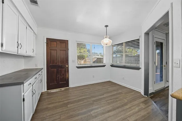 a view of an empty room with window and wooden floor