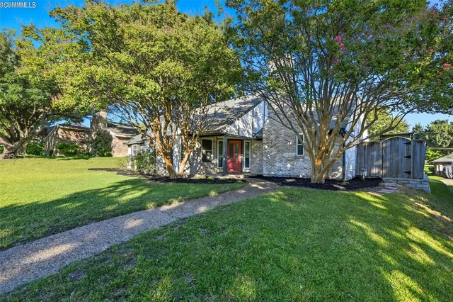 a view of a house with a big yard and large trees