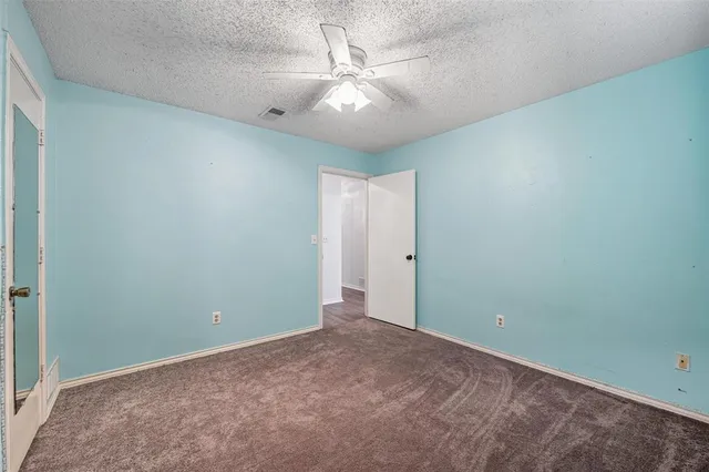 an empty room with a chandelier fan and windows