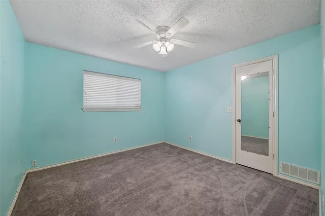 an empty room with a chandelier fan and windows