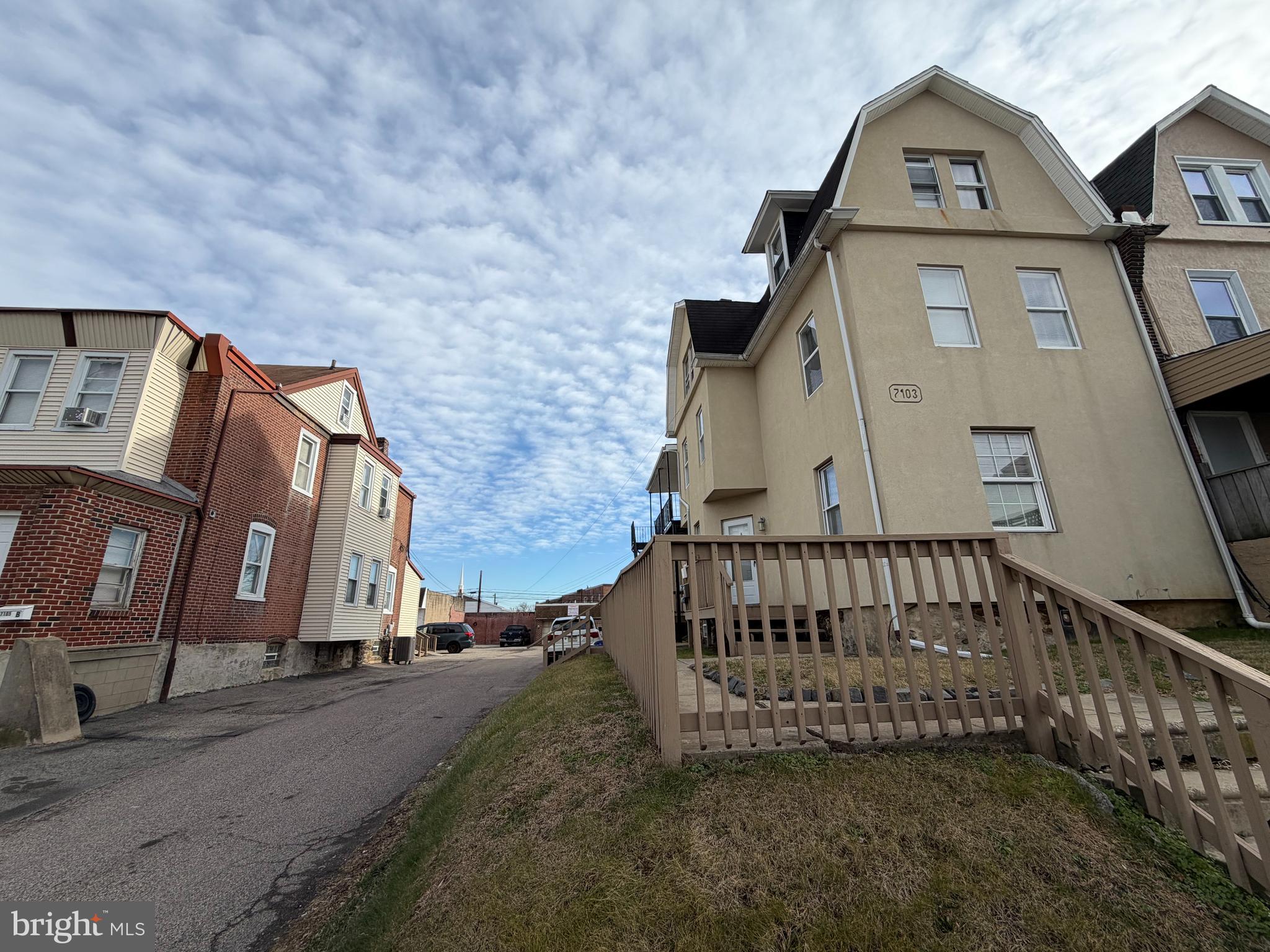 a view of a brick house with a small yard and large trees