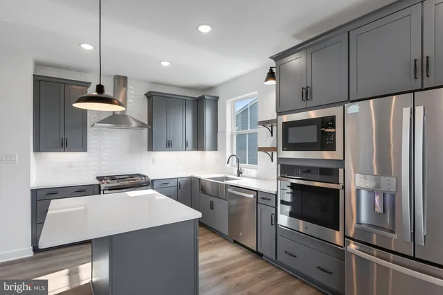 a kitchen with stainless steel appliances a sink a stove a microwave a sink a refrigerator and cabinets