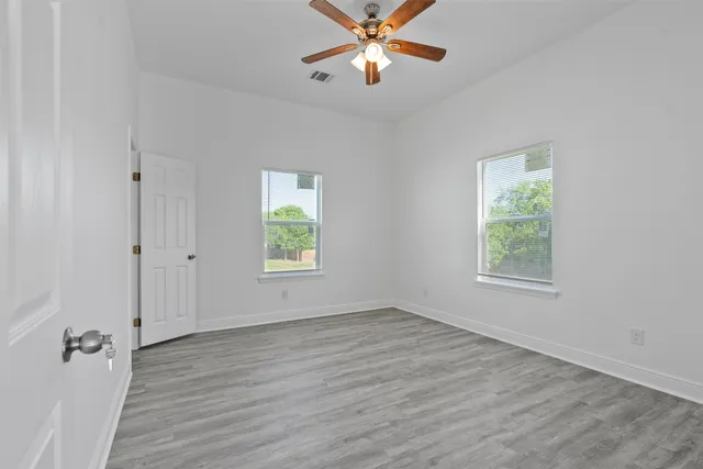 an empty room with wooden floor and windows