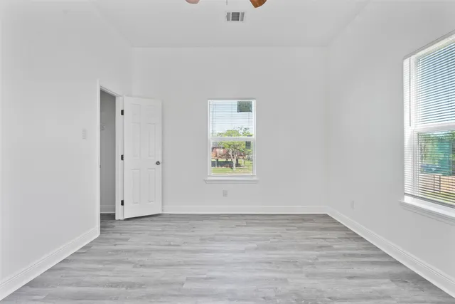 an empty room with wooden floor and windows