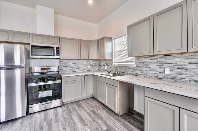 a kitchen with stainless steel appliances granite countertop a refrigerator a stove a sink and a microwave