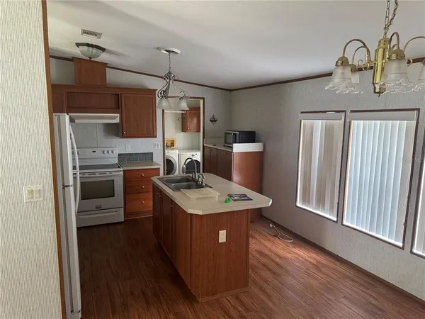 a kitchen with a refrigerator a stove top oven a sink and wooden floor