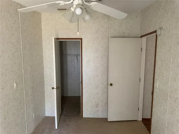 an empty room with chandelier fan and windows