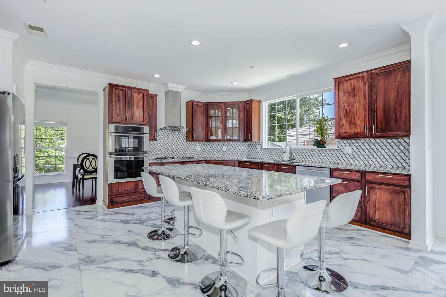 6810 Ashleys Crossing Court Temple Hills, MD 20748 - Photo 11 of 45 a kitchen with stainless steel appliances granite countertop a stove a sink a oven a dining table and chairs