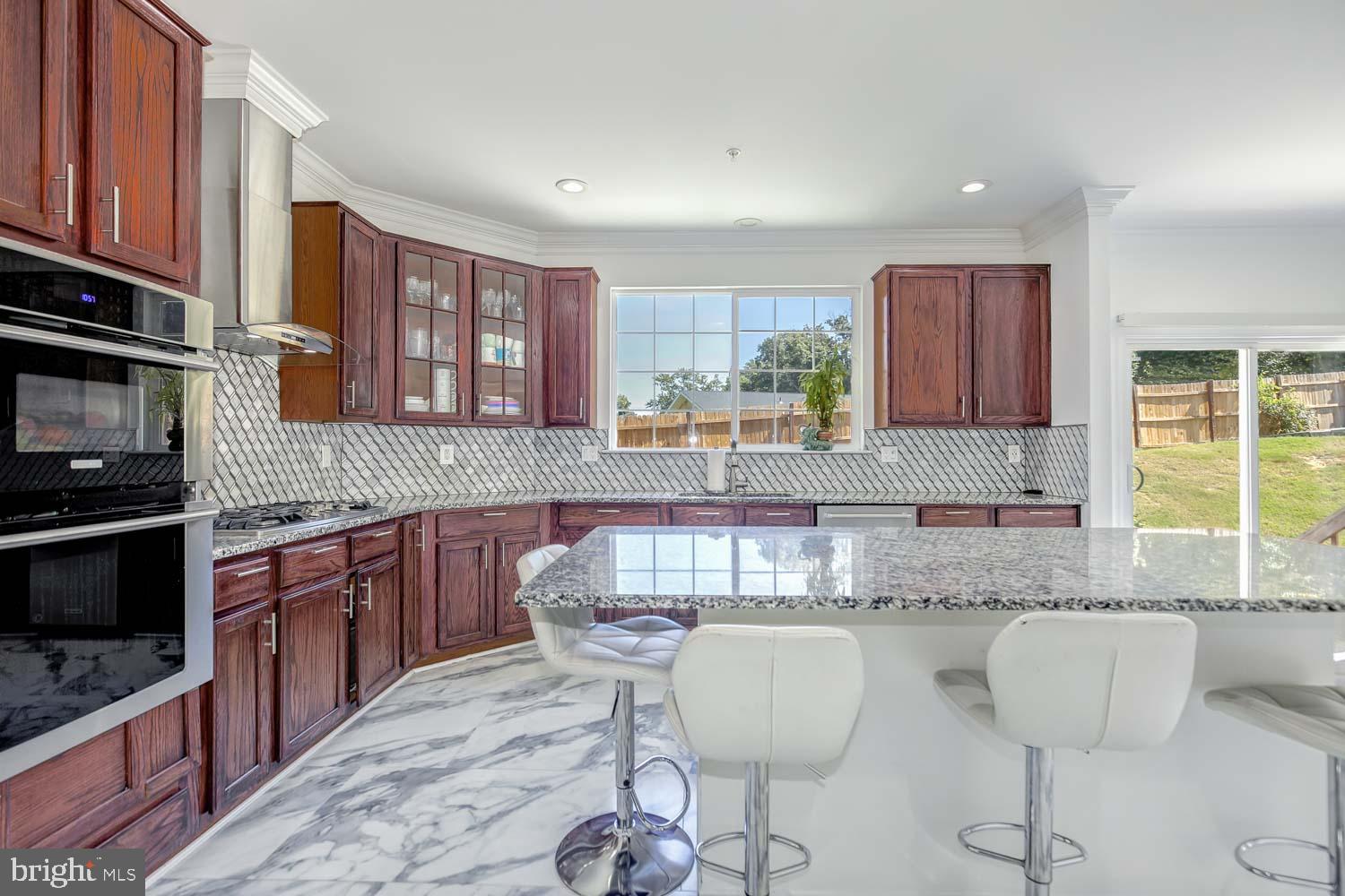 6810 Ashleys Crossing Court Temple Hills, MD 20748 - Photo 12 of 45 a kitchen with stainless steel appliances granite countertop a stove a sink a microwave cabinets and a dining table