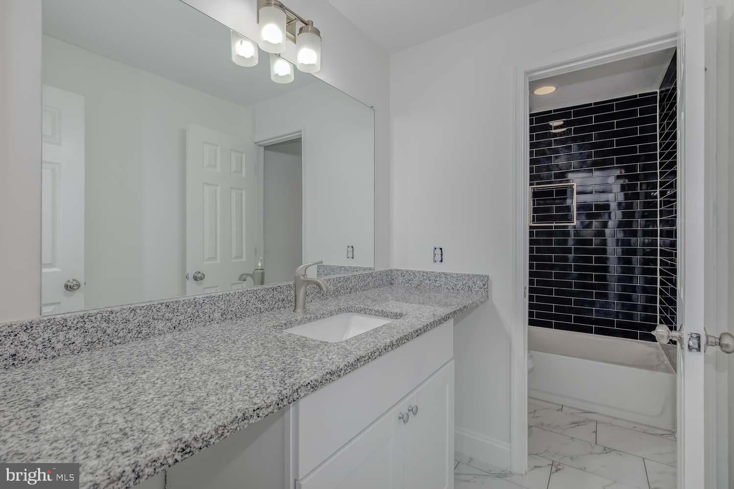 6810 Ashleys Crossing Court Temple Hills, MD 20748 - Photo 30 of 45 a bathroom with a granite countertop sink a vanity and a shower