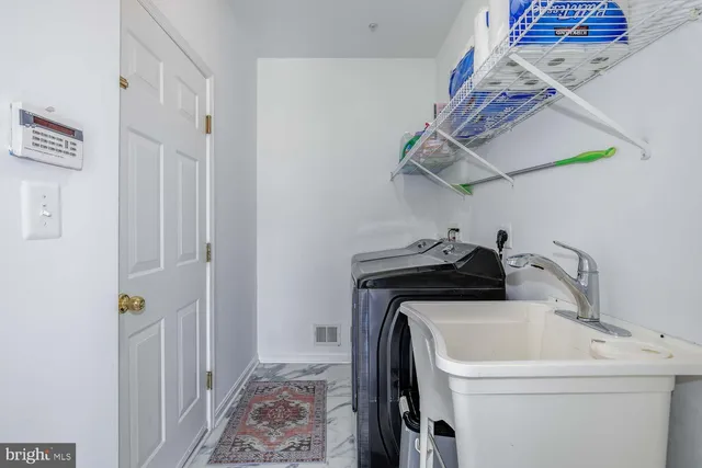 a large white kitchen with granite countertop a table chairs and a refrigerator