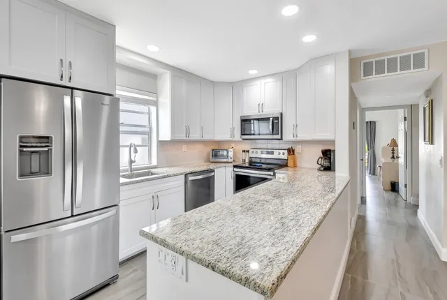 a kitchen with granite countertop a sink stove and refrigerator
