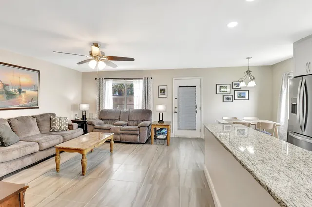 a kitchen with stainless steel appliances granite countertop a refrigerator a stove top oven a dining table and chairs with wooden floor