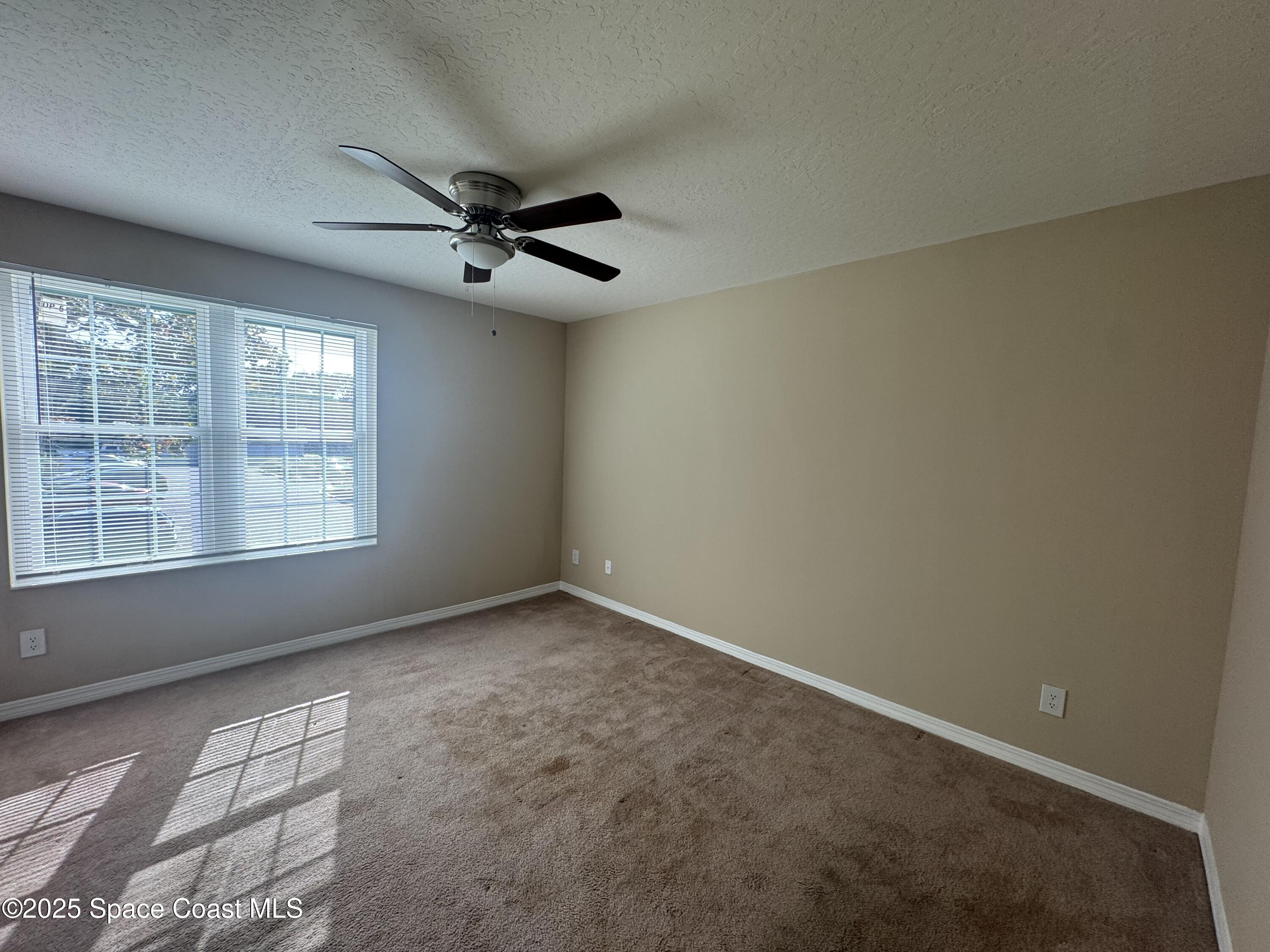 7667 North Wickham Road, Unit 1013 Melbourne, FL 32940 - Photo 8 of 14 an empty room with windows and fan