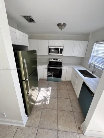 a kitchen with granite countertop a refrigerator stove and sink