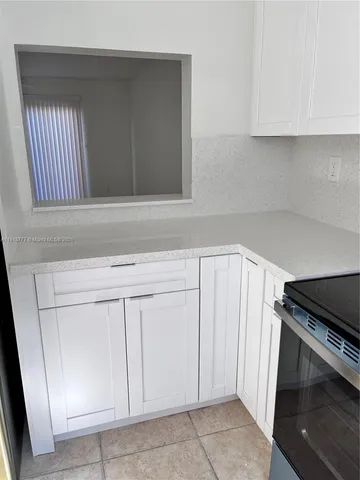 a kitchen with white cabinets and sink