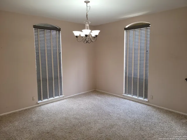 a view of a livingroom with a chandelier fan and windows