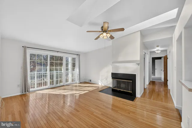 a view of an empty room with wooden floor fireplace and a window