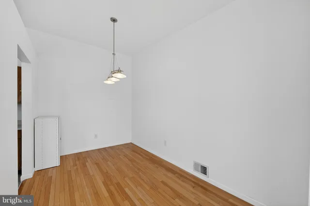a view of empty room with wooden floor and ceiling fan