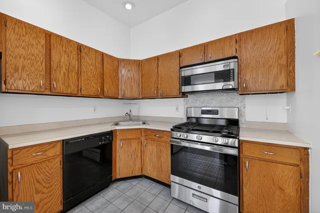 a kitchen with stainless steel appliances granite countertop wooden cabinets stove top oven and sink