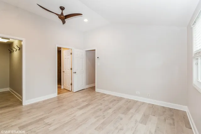 a view of empty room with wooden floor and ceiling fan