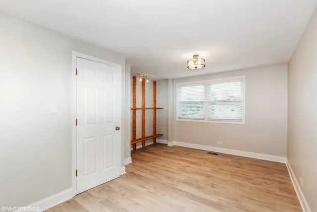an empty room with wooden floor cabinet and windows
