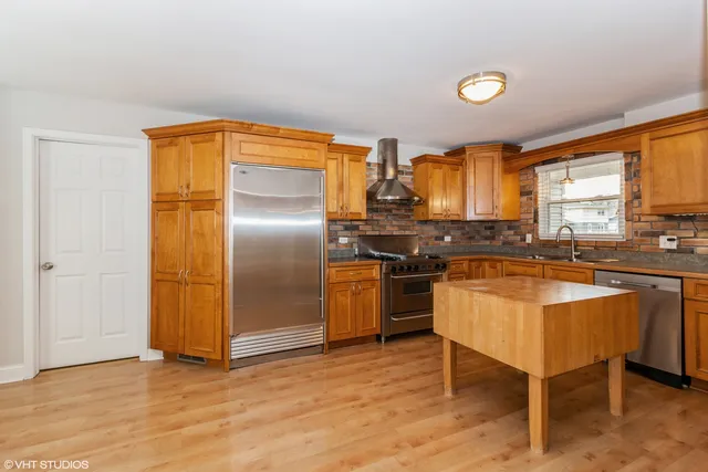 a kitchen with stainless steel appliances granite countertop a stove a sink and a refrigerator