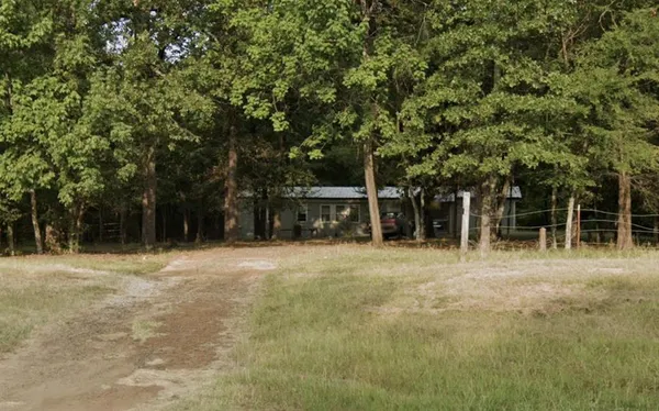 a front view of a house with a yard and trees