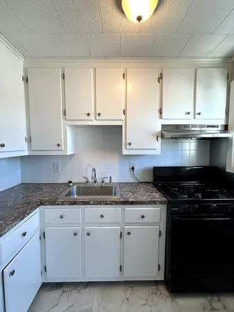 a kitchen with granite countertop white cabinets and stainless steel appliances