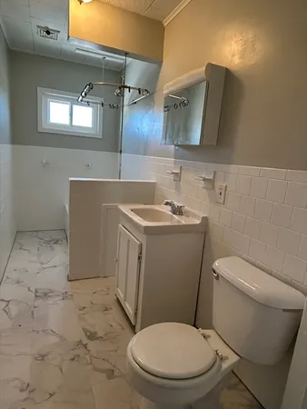 a white toilet sitting next to a bathroom sink and a mirror