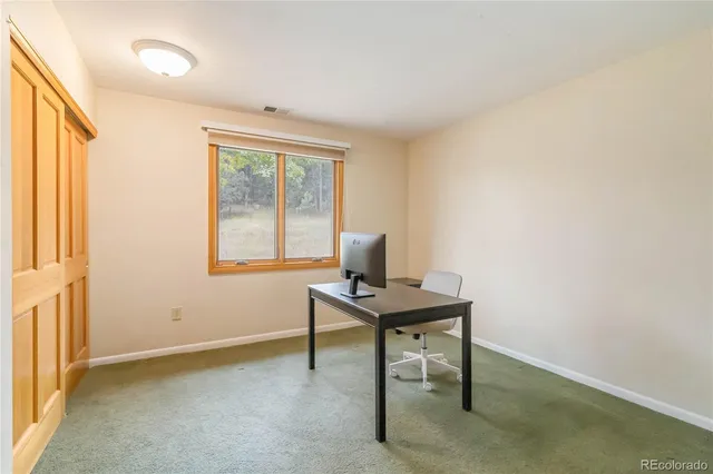 a view of a workspace with furniture and a window