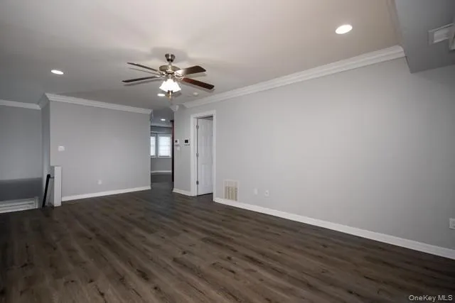 a view of an empty room with wooden floor and a ceiling fan